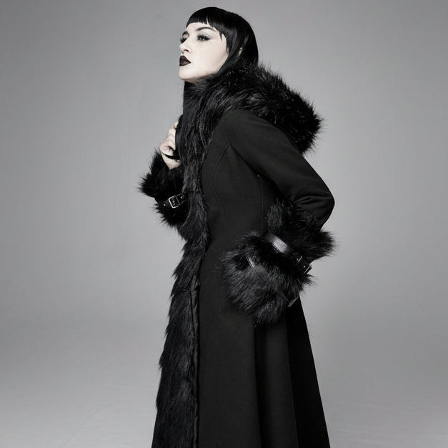 Woman wearing a black coat with fur trim against a gray background