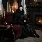 Woman in a dark, elegant room with candles and a fireplace.
